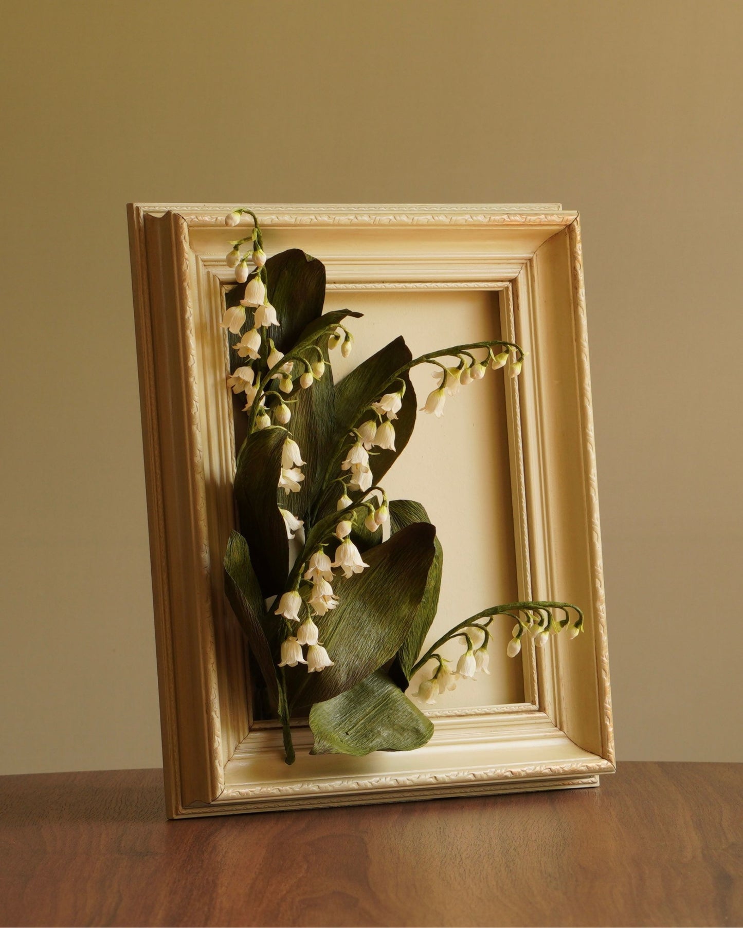 Angled view of lily of the valley paper artwork showing depth, layered leaves and flowers extending beyond the frame