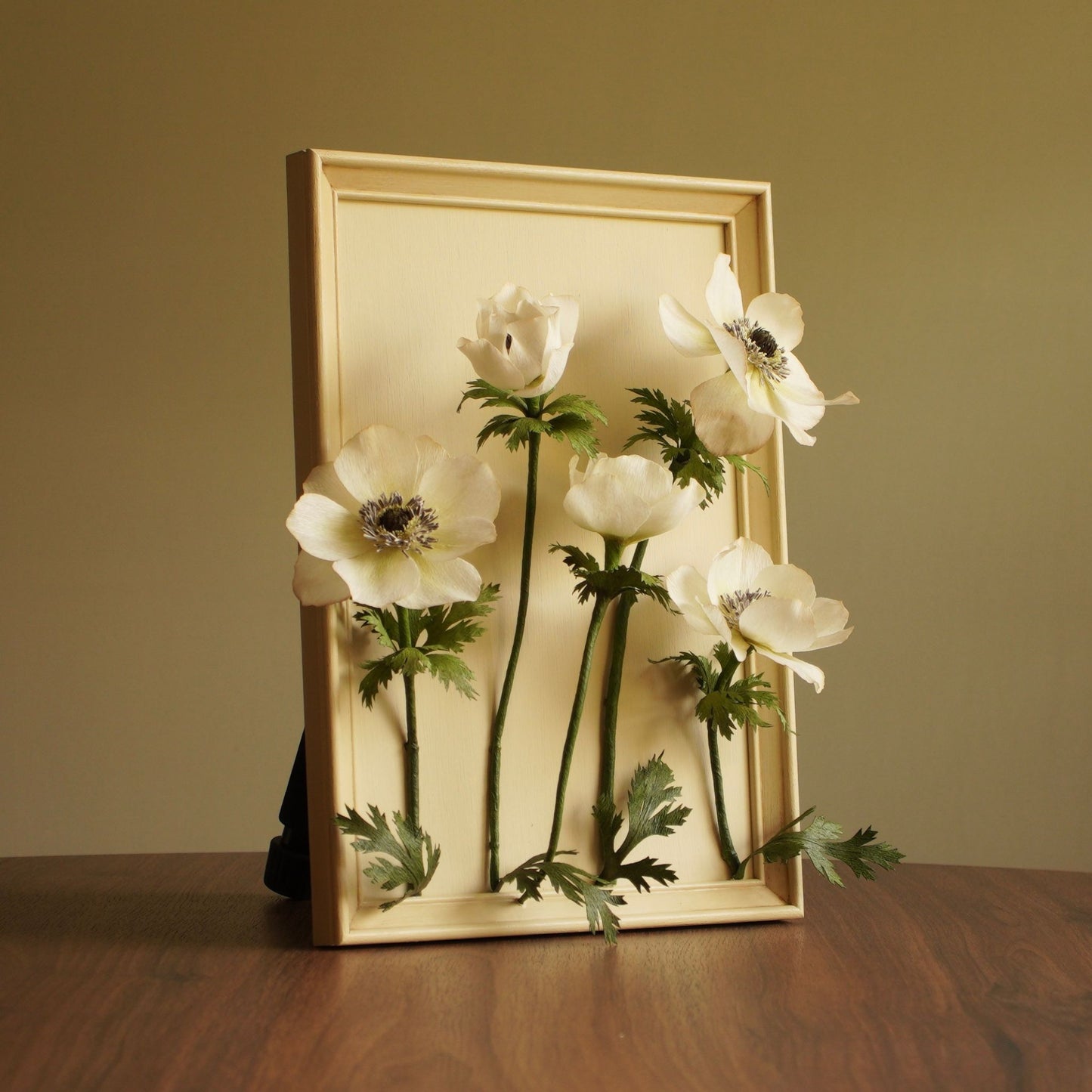 Framed paper anemone artwork featuring five white anemone blooms on a hand painted backing within an aged wooden fram