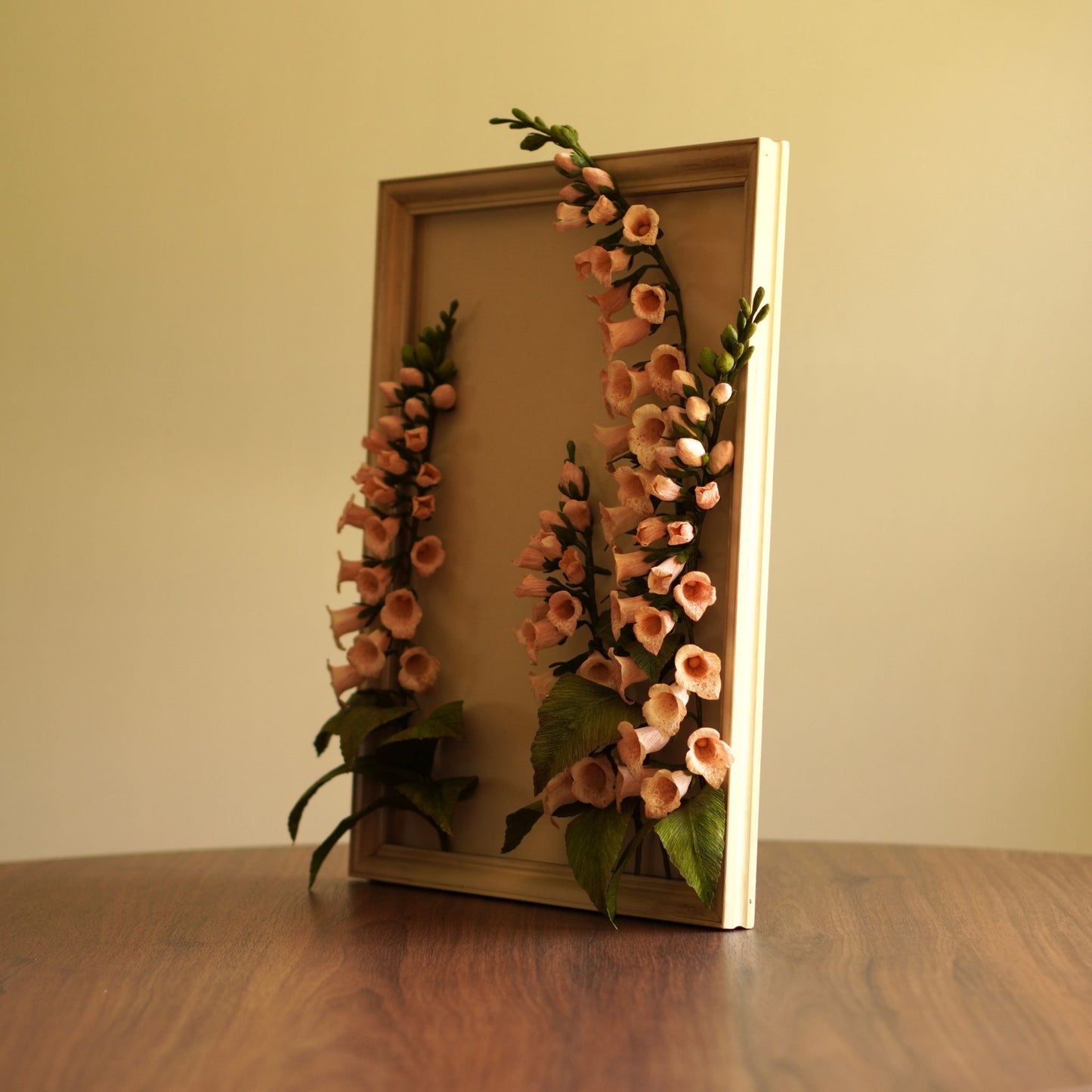 Side perspective of foxglove paper flower artwork in a painted frame with stem detail