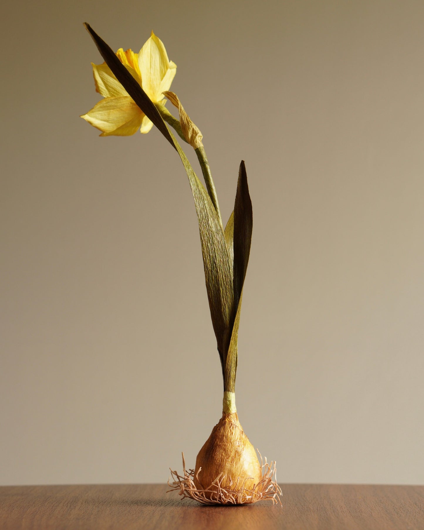 rear angled view of paper daffodil sculpture showing stem, leaves and bloom