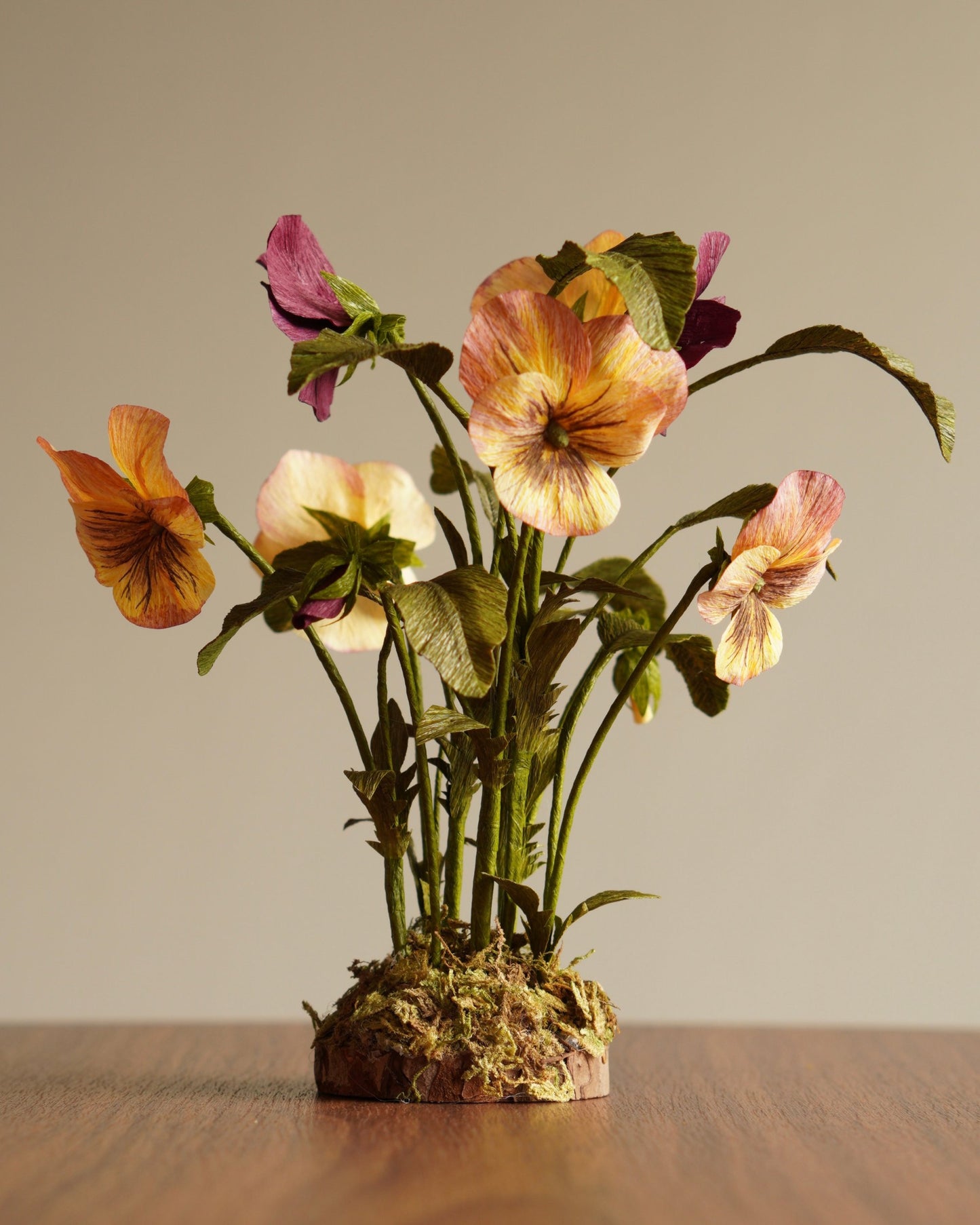 Angled view of paper pansy sculpture showing multiple blooms, buds and foliage